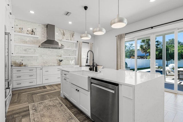 kitchen featuring dishwasher, a kitchen island with sink, white cabinets, sink, and wall chimney exhaust hood