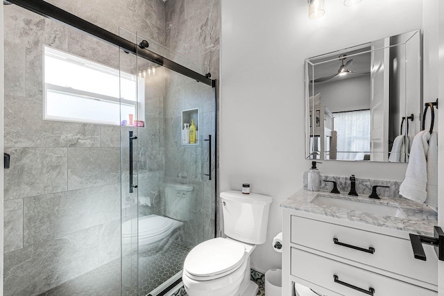 bathroom featuring an enclosed shower, vanity, toilet, and ceiling fan