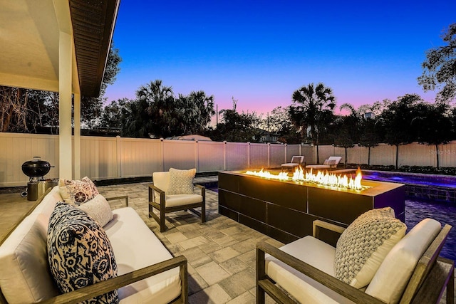 patio terrace at dusk with an outdoor living space with a fire pit