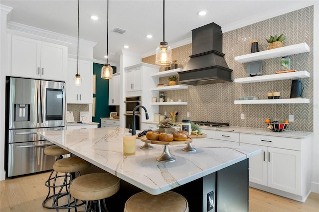 kitchen featuring white cabinetry, appliances with stainless steel finishes, custom range hood, and a kitchen island with sink