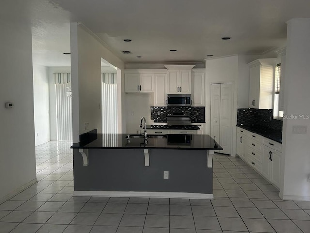 kitchen with white cabinetry, sink, stainless steel appliances, a kitchen bar, and light tile patterned floors