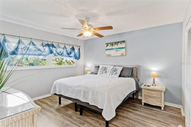 bedroom featuring ceiling fan, a closet, wood-type flooring, and a textured ceiling