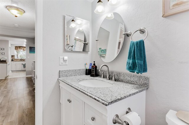 bathroom featuring hardwood / wood-style floors, vanity, toilet, and a textured ceiling