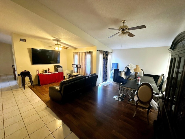 living room with ceiling fan, light tile patterned floors, and a textured ceiling