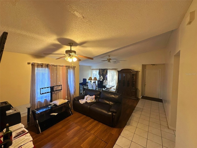 living room featuring a textured ceiling, tile patterned floors, ceiling fan, and lofted ceiling