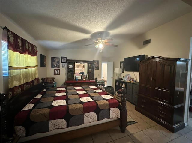 bedroom with a textured ceiling, ceiling fan, light tile patterned floors, and vaulted ceiling
