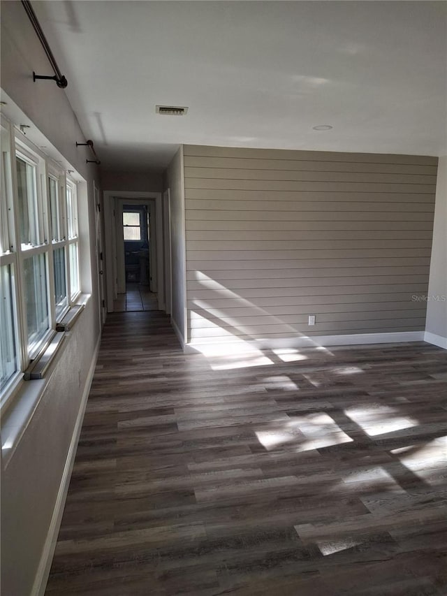 corridor with dark wood-type flooring and wood walls