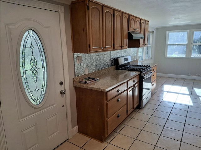 kitchen featuring stainless steel gas stove, decorative backsplash, and light tile patterned floors