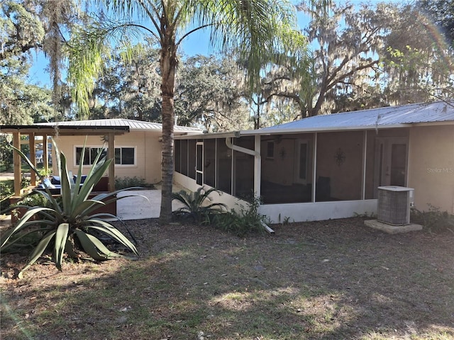 rear view of property featuring a sunroom and central AC