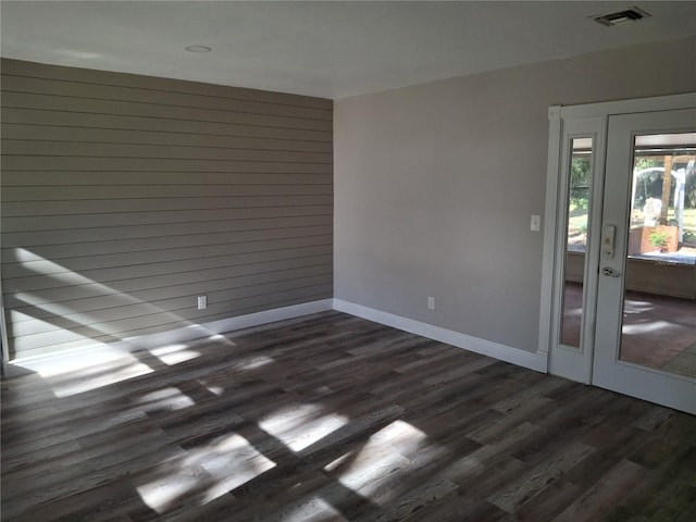 empty room with wood walls and dark wood-type flooring