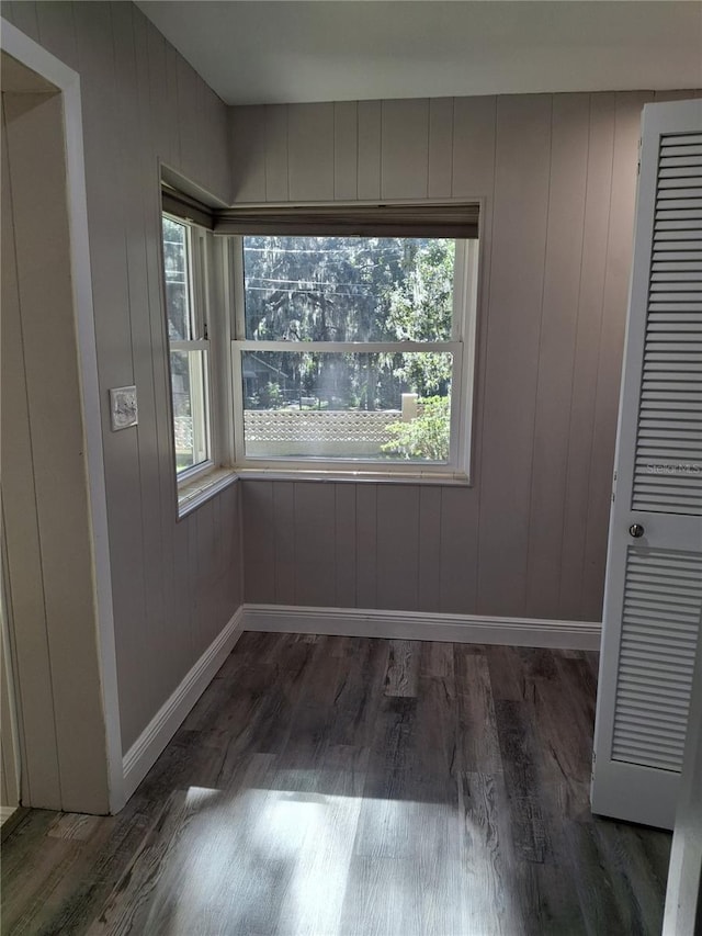 spare room featuring dark hardwood / wood-style floors and wood walls