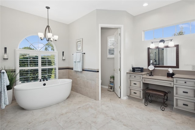 bathroom with vanity, a tub to relax in, a notable chandelier, and tile walls