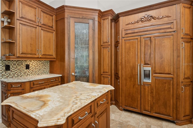 kitchen with decorative backsplash, light stone countertops, and a kitchen island