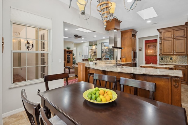 dining space with sink, ceiling fan, and a skylight