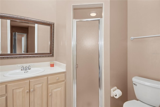 bathroom featuring a shower with door, vanity, and toilet