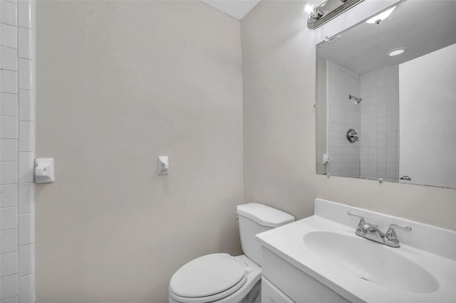 bathroom with tiled shower, vanity, and toilet