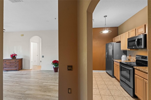 kitchen with light brown cabinetry, light wood-type flooring, stainless steel appliances, stone countertops, and hanging light fixtures