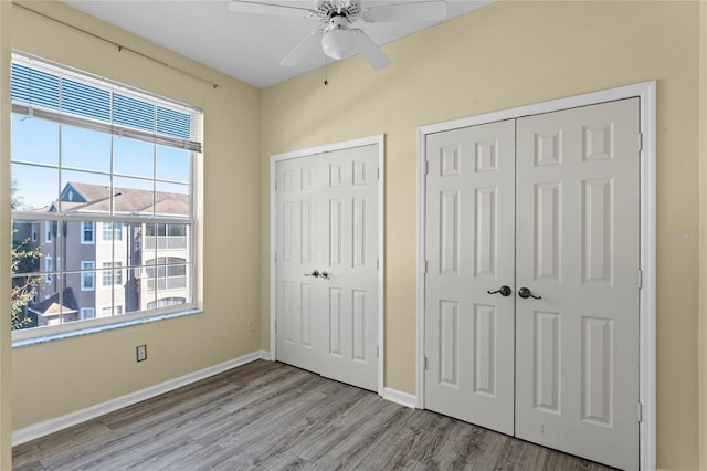 7135 Yacht Basin Ave Unit 237, Orlando, FL 32835 - unfurnished bedroom featuring two closets, wood finished floors, baseboards, and a ceiling fan