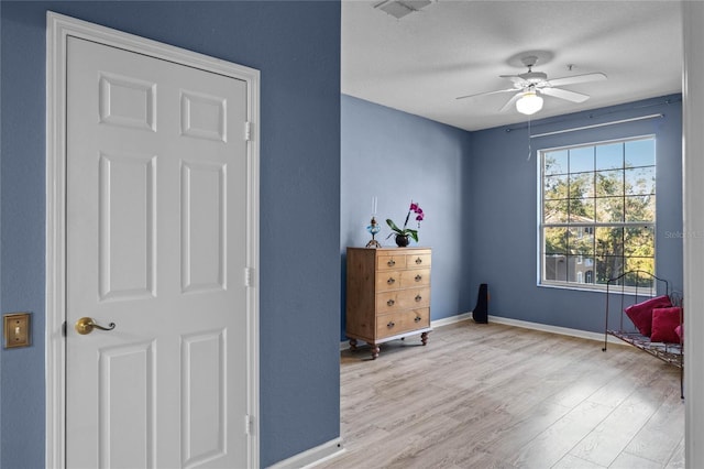 living area with ceiling fan, light hardwood / wood-style flooring, and a textured ceiling