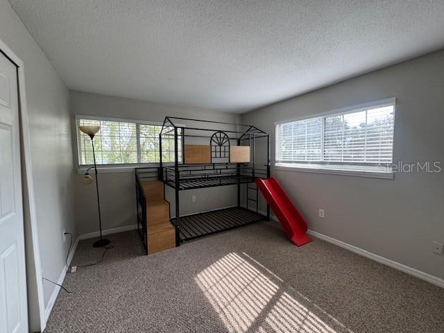 carpeted bedroom featuring a textured ceiling and multiple windows