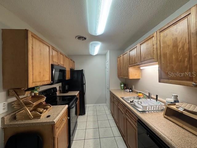 kitchen featuring light tile patterned flooring, a textured ceiling, sink, and black appliances