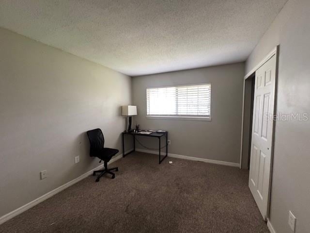 interior space featuring dark carpet and a textured ceiling