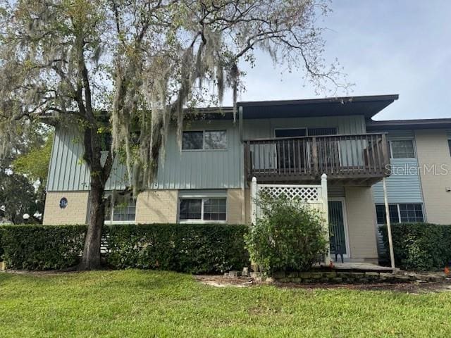 rear view of house with a lawn and a balcony