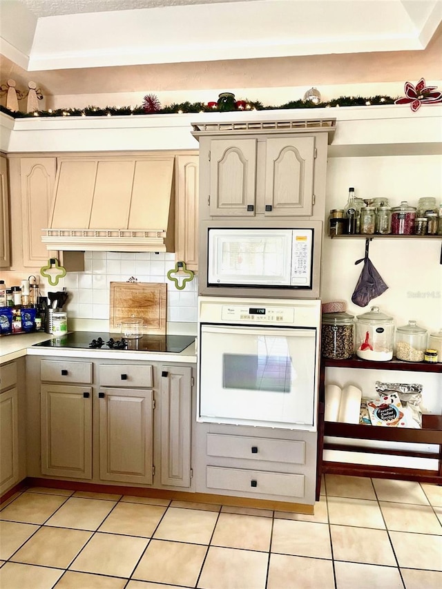 kitchen featuring decorative backsplash, custom range hood, light tile patterned floors, and white appliances