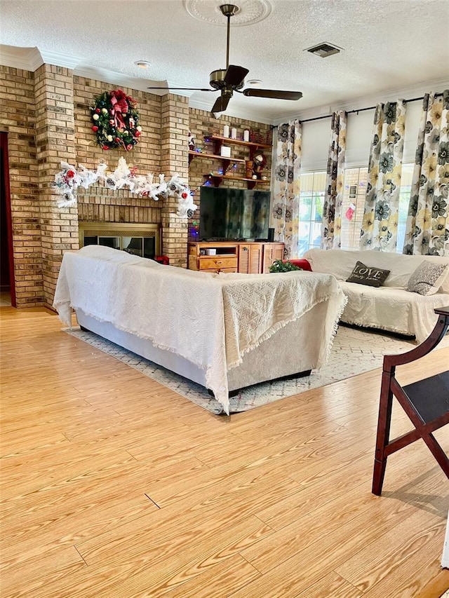 living room with hardwood / wood-style floors, brick wall, a textured ceiling, and a brick fireplace