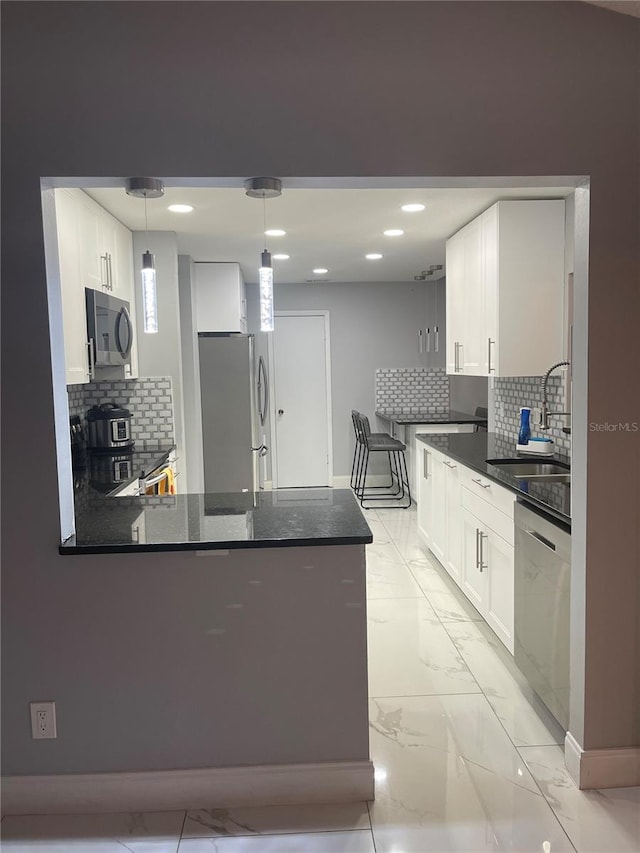 kitchen with decorative light fixtures, white cabinetry, sink, and appliances with stainless steel finishes