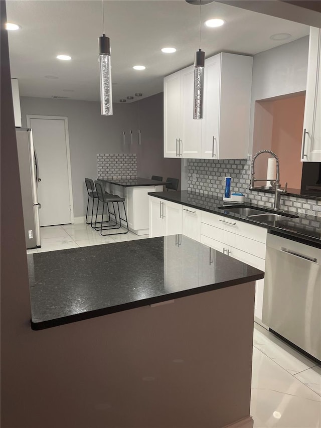 kitchen featuring white cabinetry, sink, tasteful backsplash, pendant lighting, and appliances with stainless steel finishes