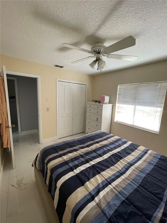 bedroom with a textured ceiling, a closet, and ceiling fan