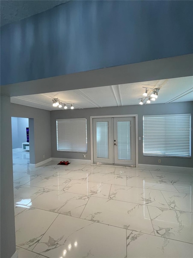 spare room featuring beam ceiling and french doors