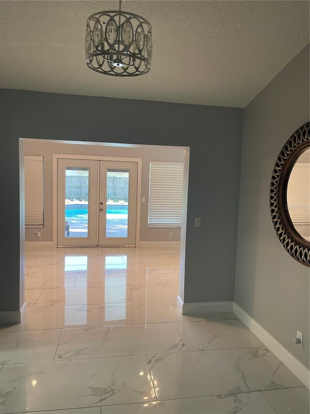 interior space with a textured ceiling and french doors