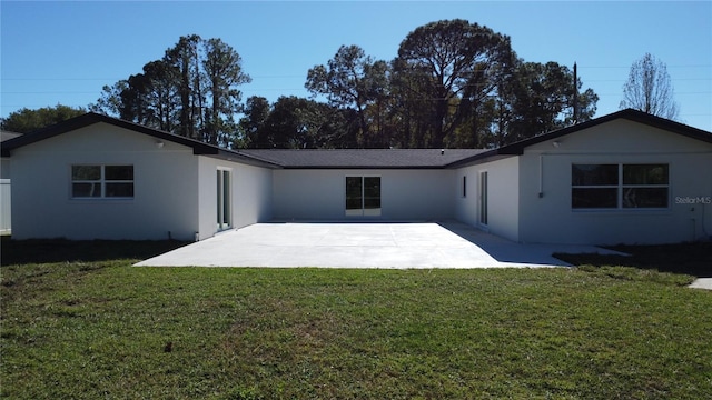 rear view of house featuring a lawn and a patio