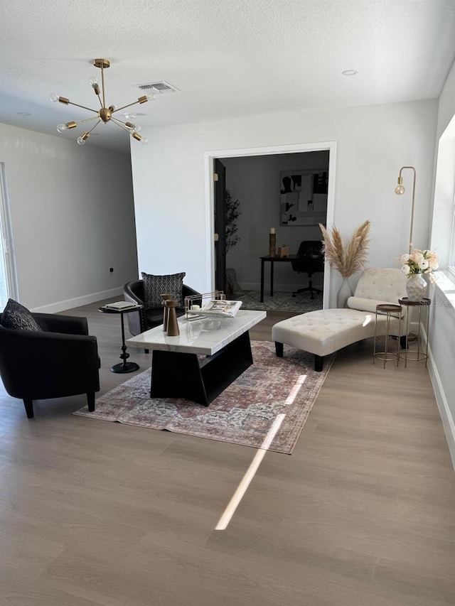 living room with a textured ceiling, light wood-type flooring, and an inviting chandelier