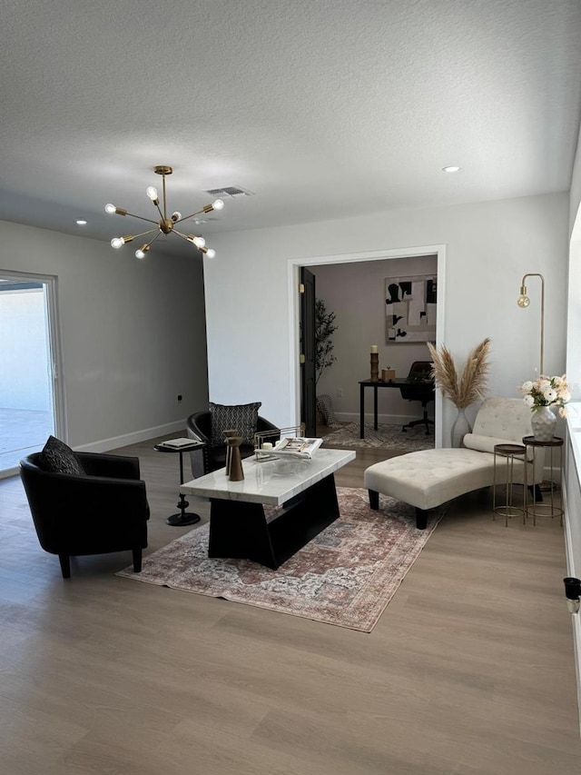 living room with an inviting chandelier, a textured ceiling, and light hardwood / wood-style flooring