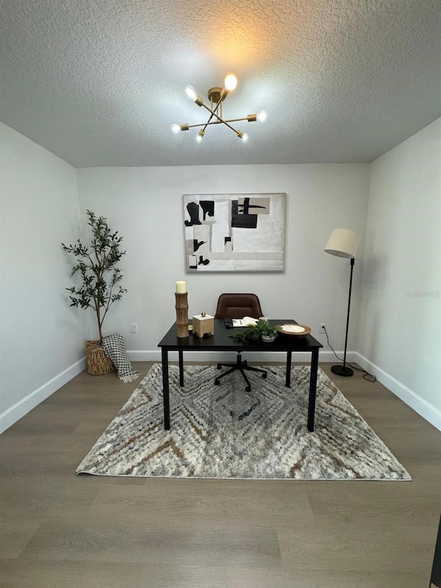 office area with a textured ceiling, hardwood / wood-style flooring, and a notable chandelier