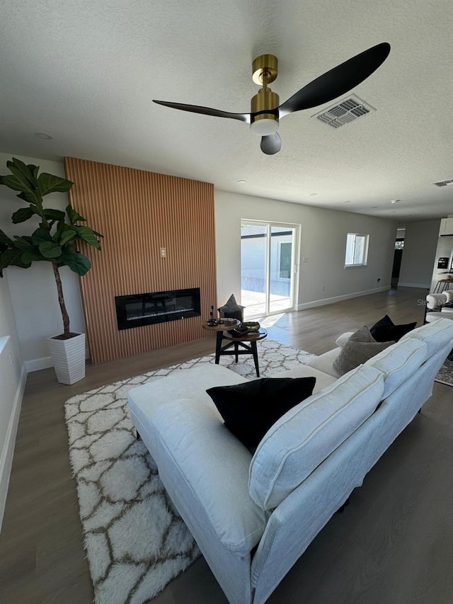 living room featuring a textured ceiling, hardwood / wood-style flooring, and ceiling fan