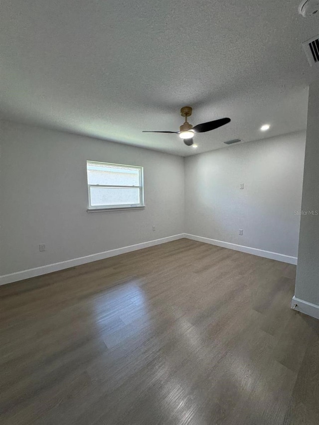 empty room with dark hardwood / wood-style floors, ceiling fan, and a textured ceiling