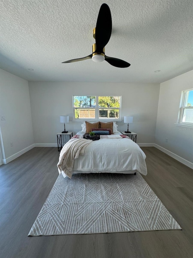 bedroom with multiple windows, ceiling fan, and dark hardwood / wood-style floors