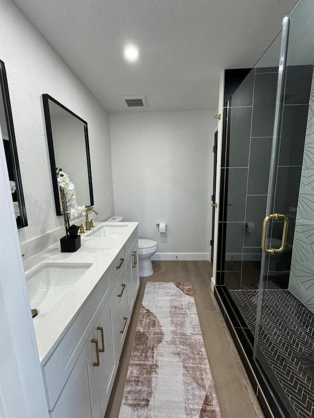 bathroom with hardwood / wood-style floors, vanity, toilet, a textured ceiling, and an enclosed shower