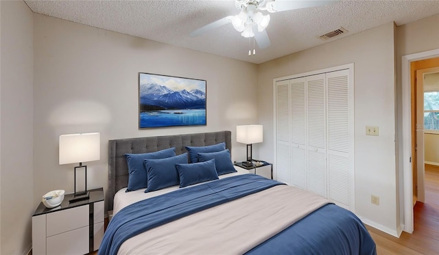 bedroom with ceiling fan, a closet, a textured ceiling, and light wood-type flooring