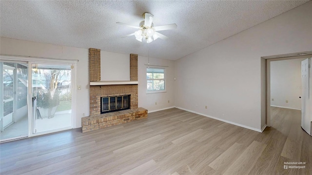 unfurnished living room with a fireplace, vaulted ceiling, a textured ceiling, and light wood-type flooring