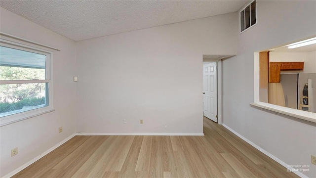 spare room with light hardwood / wood-style flooring and a textured ceiling