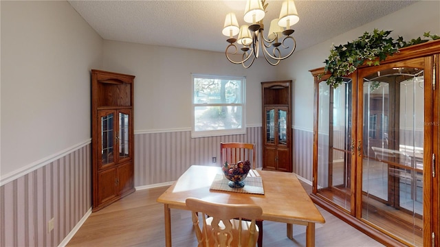 dining space featuring a chandelier, a textured ceiling, and light hardwood / wood-style flooring