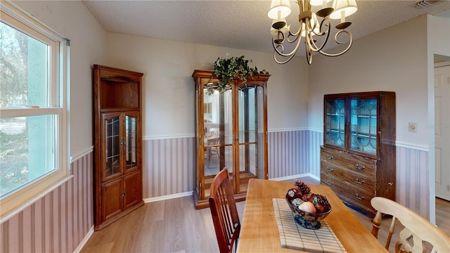 dining area featuring wood-type flooring, a chandelier, and a textured ceiling