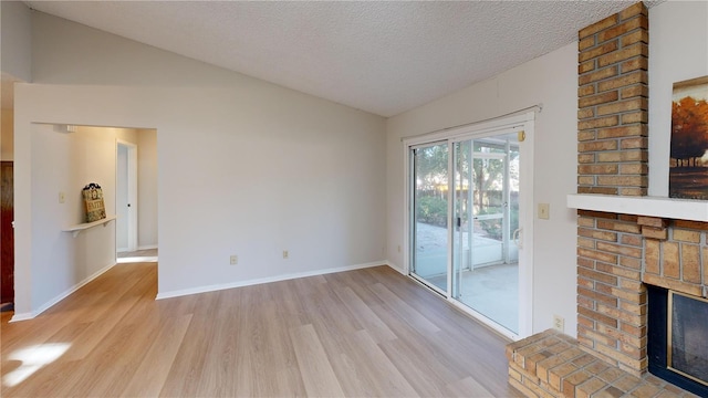 unfurnished living room with vaulted ceiling, light wood-type flooring, a textured ceiling, and a fireplace