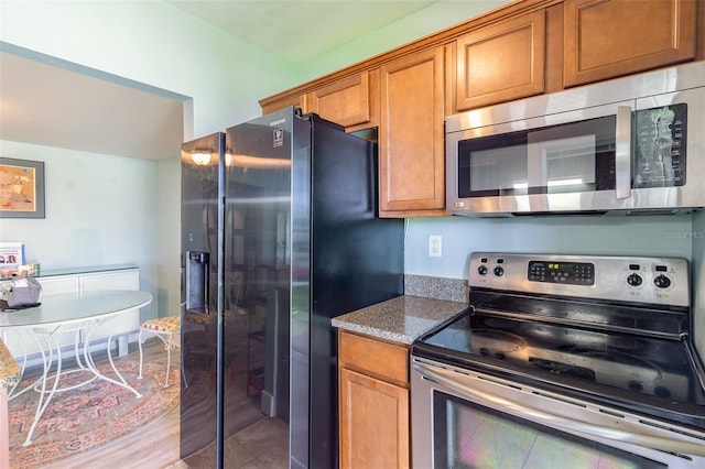 kitchen with light stone countertops, light tile patterned floors, and stainless steel appliances