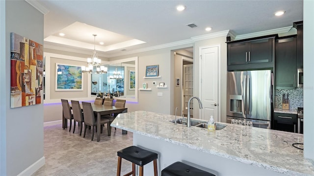 kitchen featuring sink, an inviting chandelier, decorative light fixtures, a tray ceiling, and appliances with stainless steel finishes